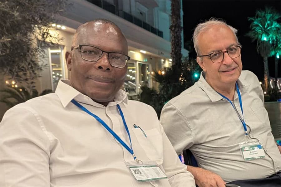 Two men with conference badges sitting outdoors at night